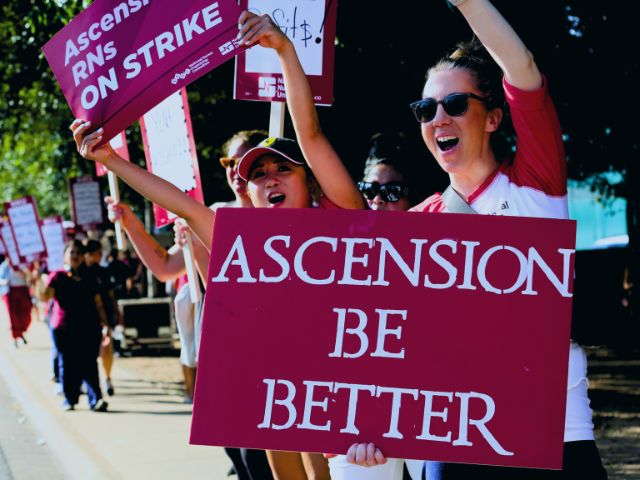 Nurses on strike and holding a sign that reads 