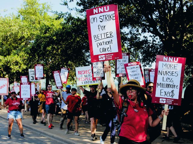 Picket line of nurses striking with signs reading 