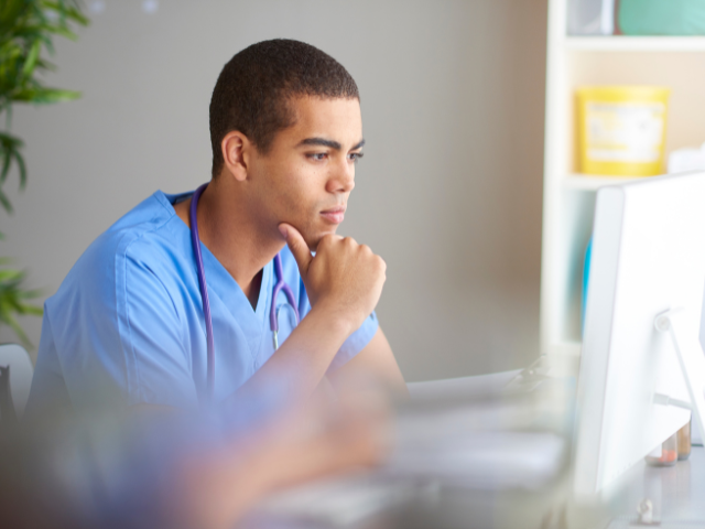 Male nurse getting ready for the West Virginia nursing license renewal at a computer.